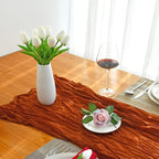 Table setting with a vase of white tulips, a glass of red wine, and a small plate with a pink flower on a wooden table.