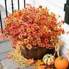 Decorative arrangement with autumn flowers in a wooden barrel, pumpkins, and fall leaves on a porch.