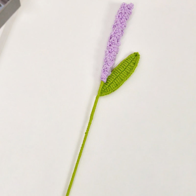 Crocheted lavender flower with a green stem on a white background