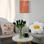 Living room with gray sofa, floral pillow, white coffee table, and wall art.