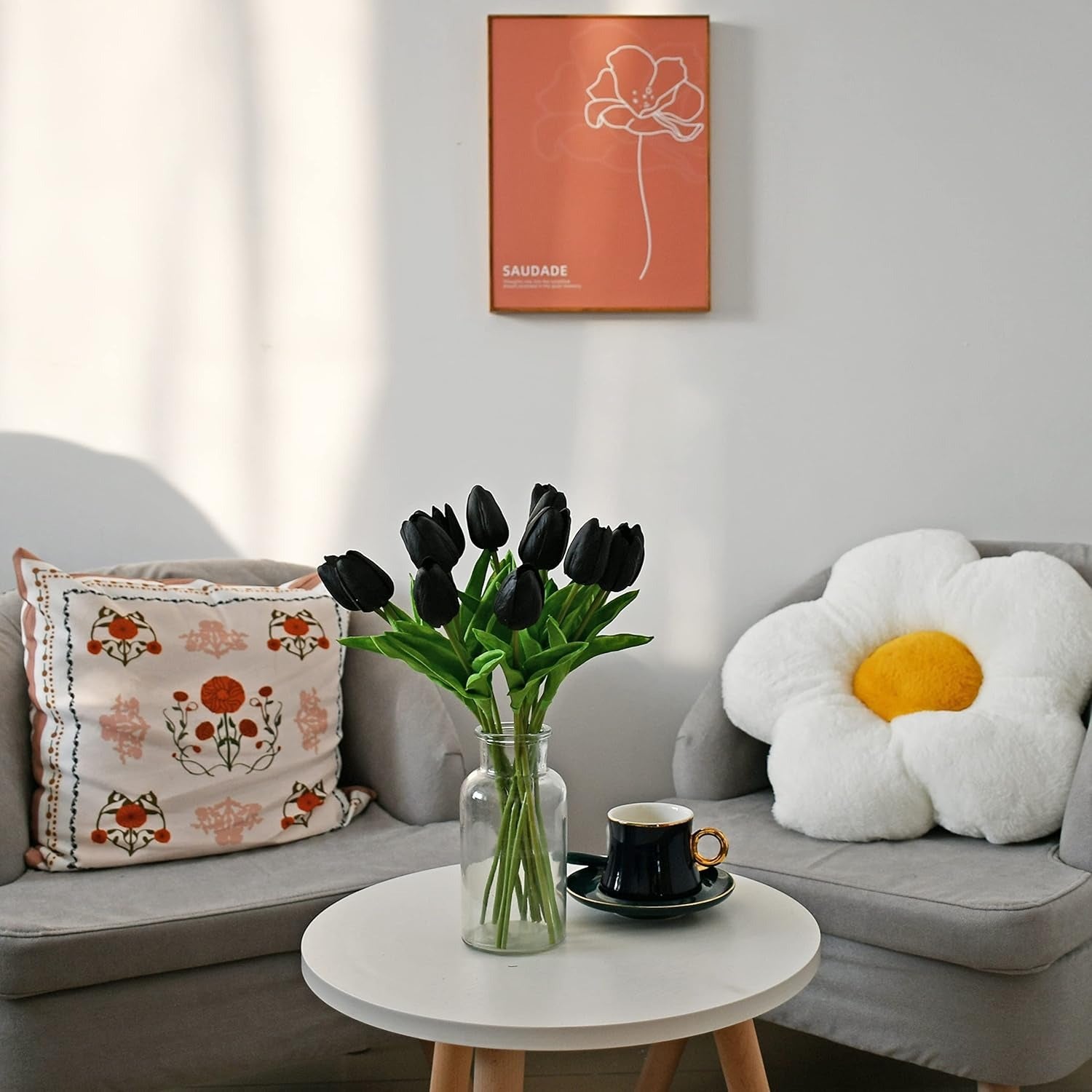 Living room with gray sofa, floral pillow, white coffee table, and wall art.