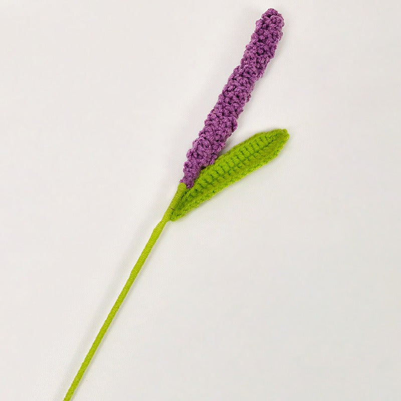 Crocheted lavender flower with a green stem on a white background