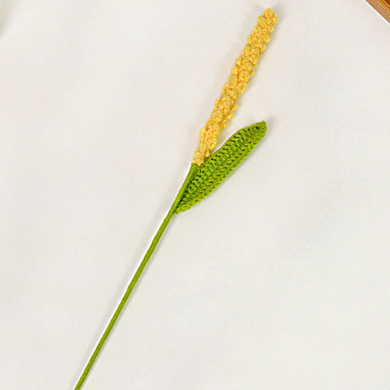 Crocheted plant with yellow flowers and green leaves on a white background