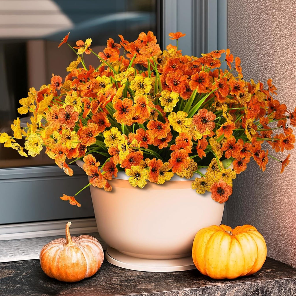 Potted plant with orange and yellow flowers on a windowsill with pumpkins.