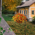 Hanging basket of orange and yellow flowers in front of a yellow house with a stone pathway.