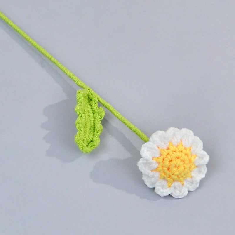 Crocheted daisy flower with green stem on a light gray background