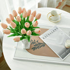 Bouquet of pink tulips on a white table with a magazine and cup in the background