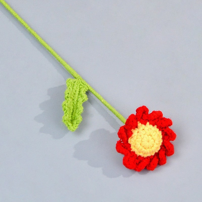 Crocheted red flower with yellow center on a gray background