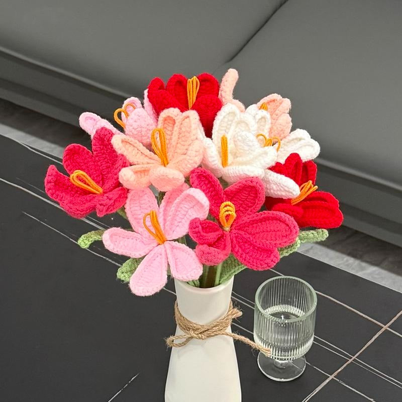 Bouquet of colorful crocheted flowers in a white vase on a dark surface.