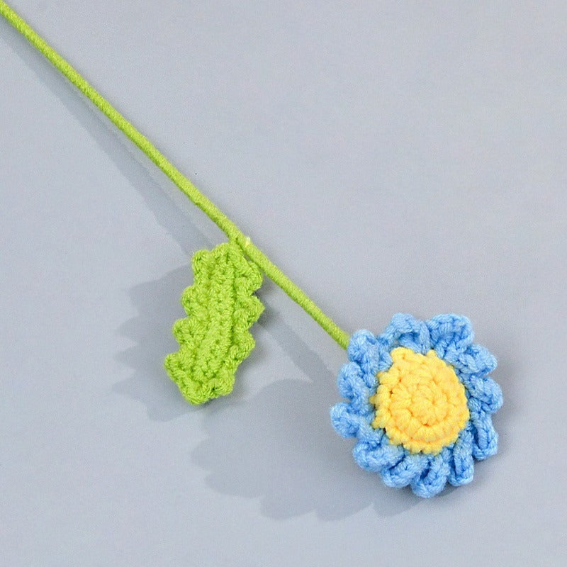 Crocheted flower and leaf on a gray background