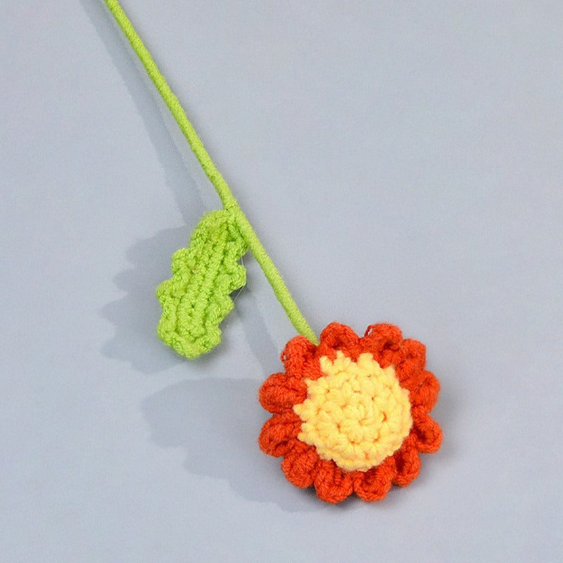 Crocheted flower and leaf on a gray background