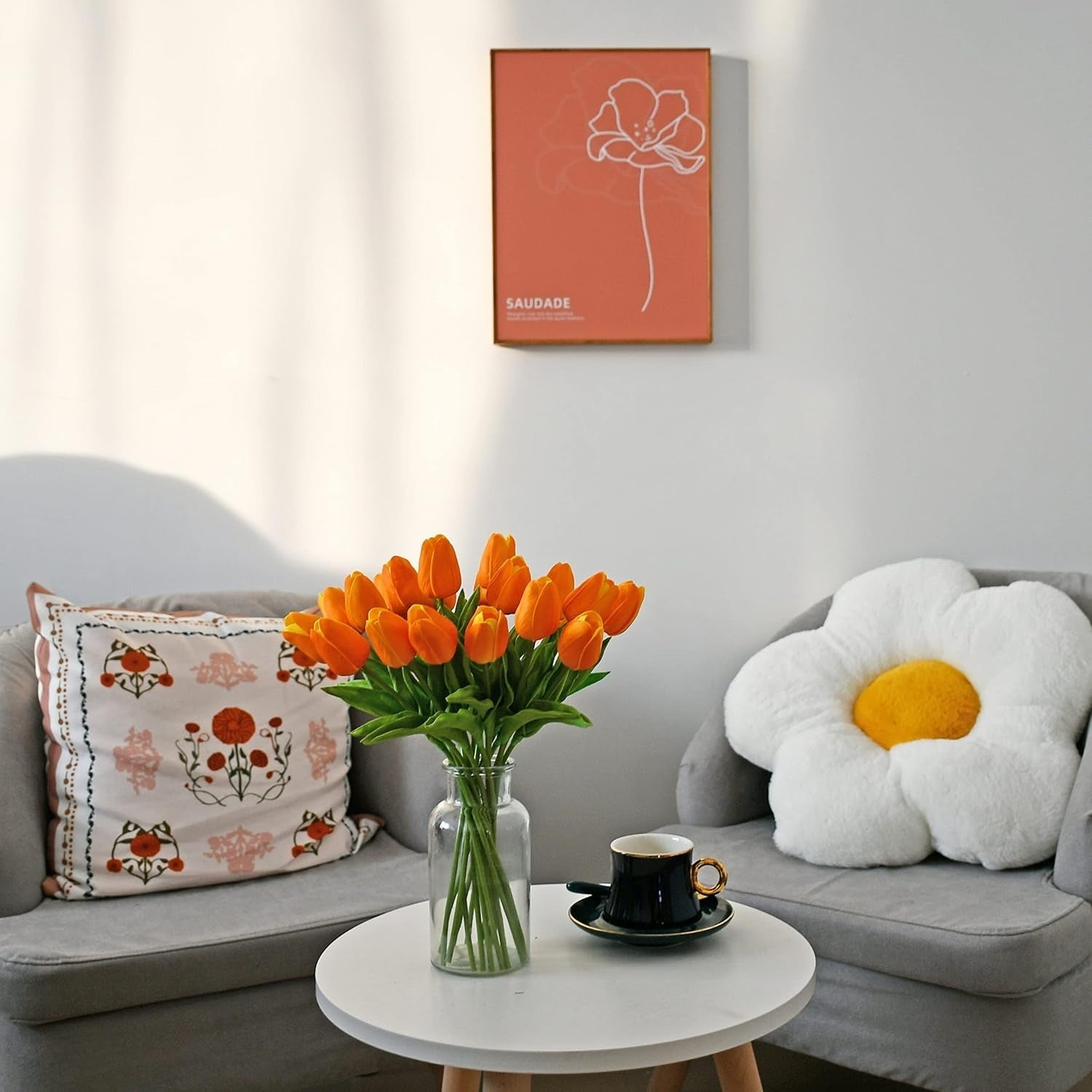 Living room with gray sofa, flower-shaped pillow, and vase of orange tulips.