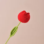 Crocheted red flower with a green stem on a beige background