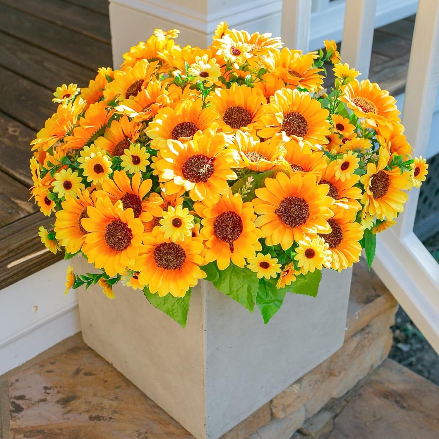 Bouquet of artificial sunflowers in a decorative pot on a wooden surface.