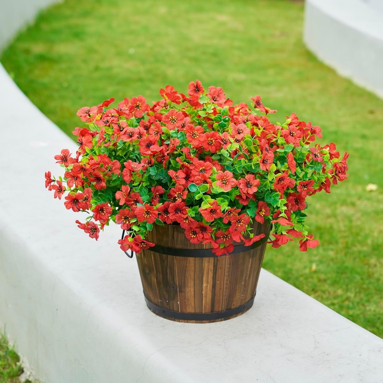 Potted plant with red flowers on a concrete surface with grass in the background