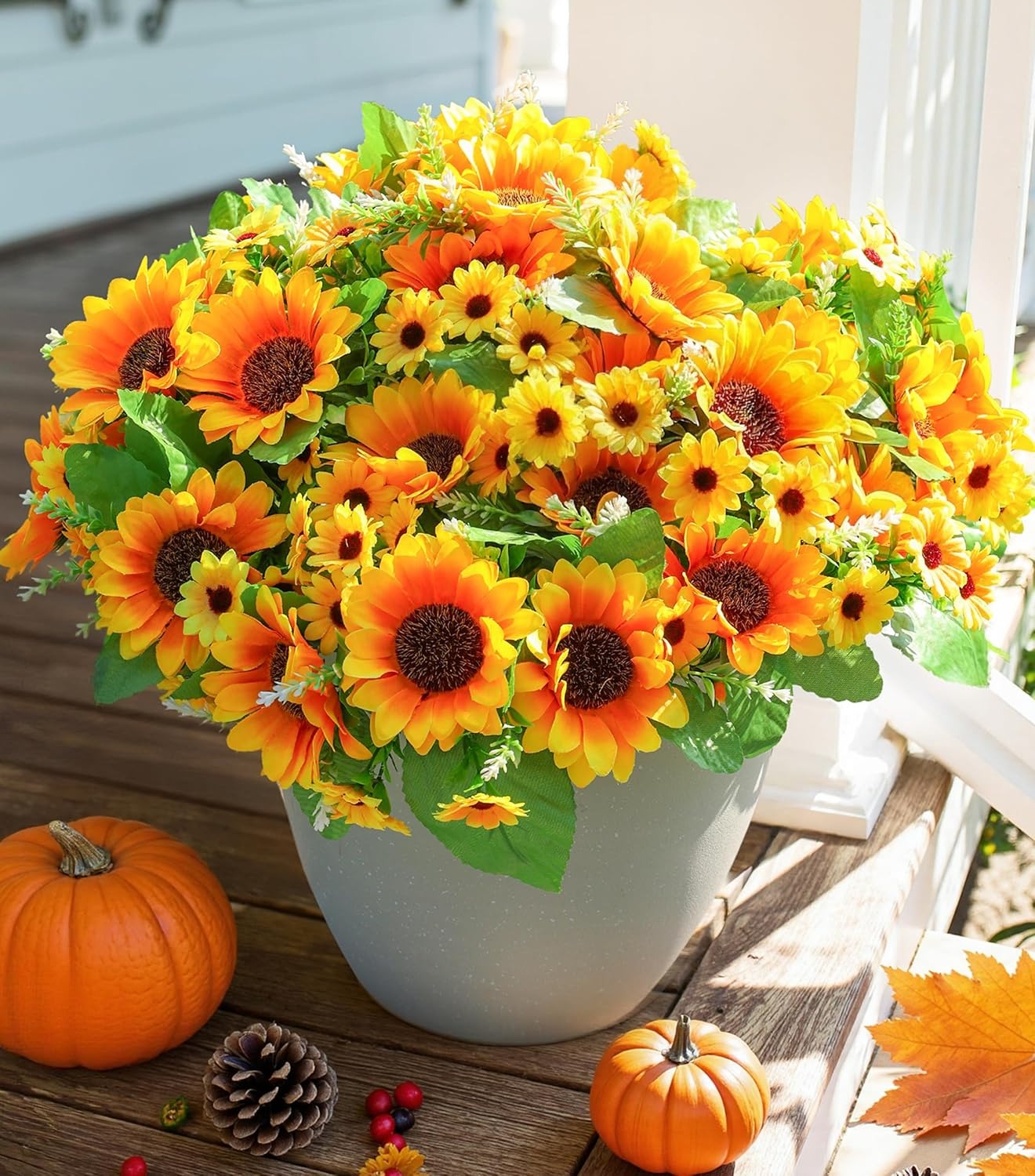 Potted sunflowers with pumpkins and pinecones on a wooden surface