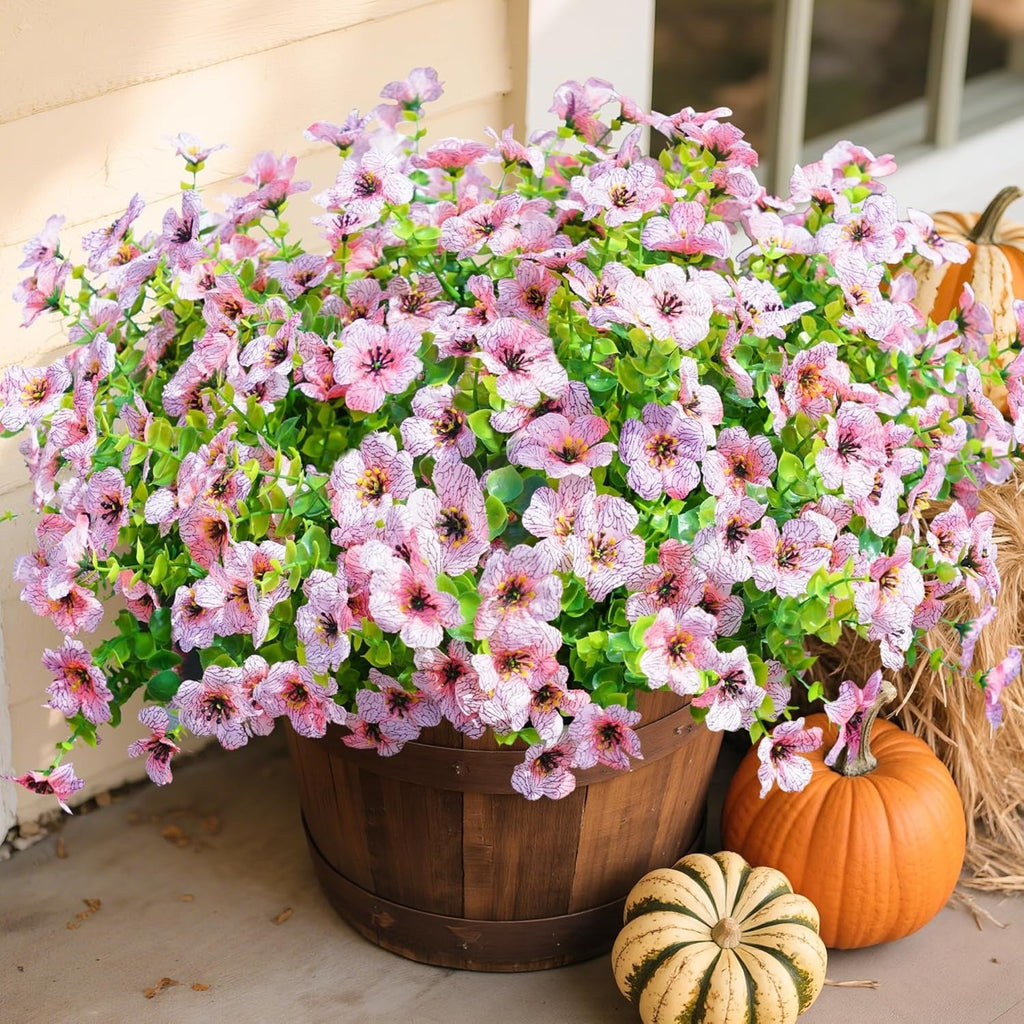 Potted plant with pink and white flowers on a patio with pumpkins