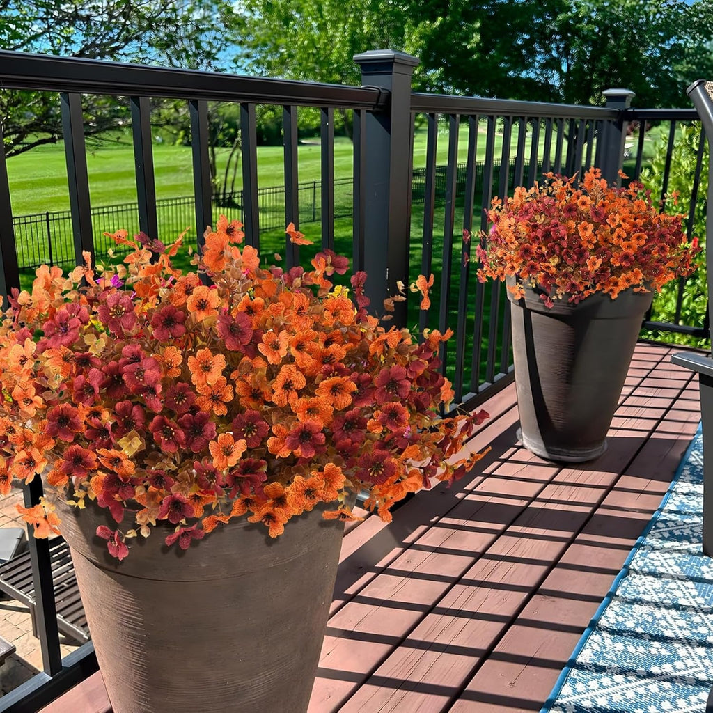 Two potted plants with orange and pink flowers on a wooden deck.