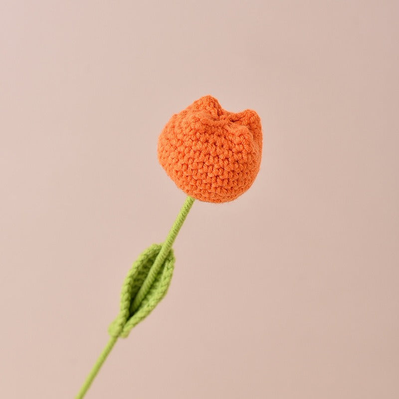 Knitted orange tulip with green stem on a beige background