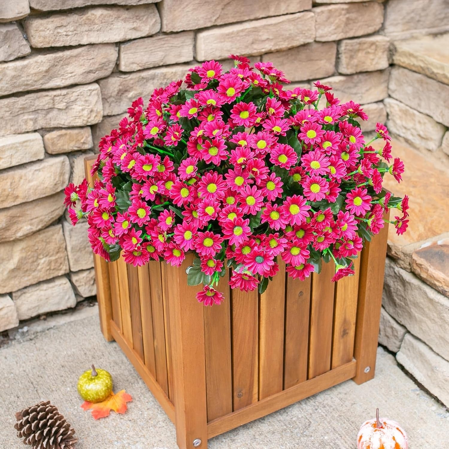 Wooden planter with pink flowers against a stone wall