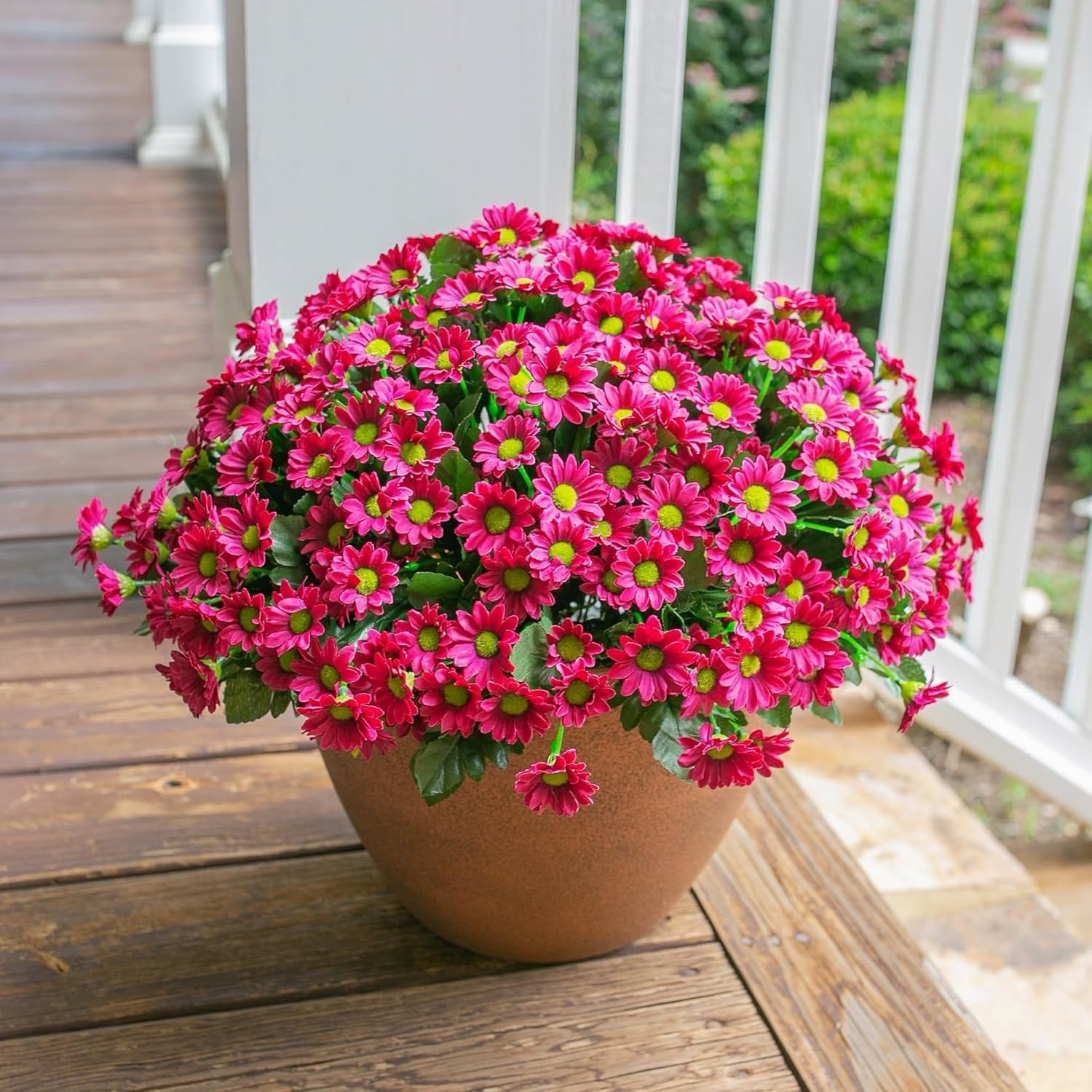 Potted plant with bright pink flowers on a wooden deck
