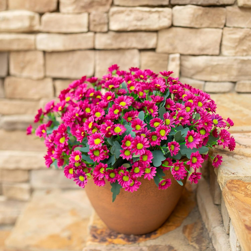 Potted plant with pink flowers against a stone wall background