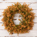 Wreath with orange and green leaves on a white wooden background