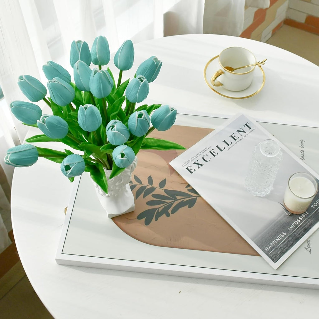Bouquet of blue tulips on a white table with a magazine and cup.
