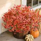 Bouquet of red flowers in a wooden basket with pumpkins and hay bale on a porch.