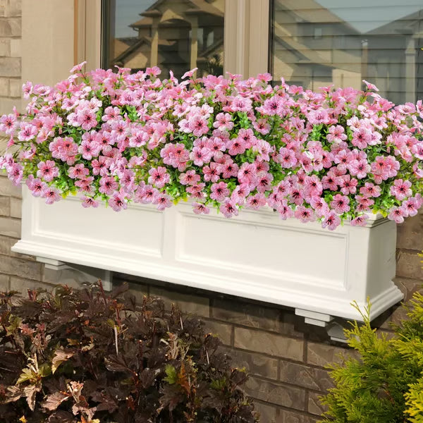White window box with pink flowers on a brick wall